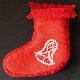 Rotes Stiefelchen mit weißen Motiven und Klöppelspitze verbunden