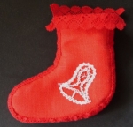 Rotes Stiefelchen mit weißen Motiven und Klöppelspitze verbunden